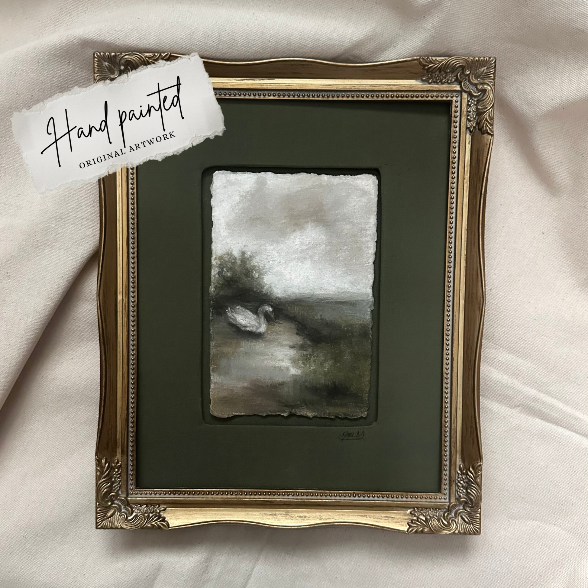 Hand-painted swan artwork in an ornate frame on a green background